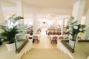 a restaurant with tables and chairs and potted plants at Paviljoni Slaven in Selce