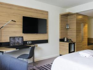 a hotel room with a desk and a television on a wall at Novotel Szczecin Centrum in Szczecin