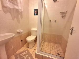 a bathroom with a shower with a toilet and a sink at Margate Boulevard Beachfront Apartment in Margate