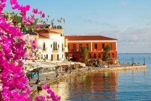 a building next to a body of water with pink flowers at Infinity Wellness Sea View Suites in Afráta