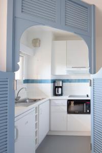 eine weiße Küche mit einer Spüle und einer Mikrowelle in der Unterkunft Résidence les Grands Pins in Gréoux-les-Bains