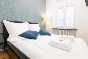 a white bed with two blue pillows and a window at MonjAna Premium Rynek in Wrocław