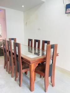 a dining room table with wooden chairs and a glass top at Kapuwatta Pool Villa in Weligama
