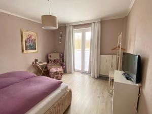 a bedroom with a bed and a tv and a chair at Apartment am Golfplatz in Obernkirchen