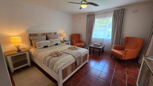 a bedroom with a bed and two chairs and a window at TheBlueDoor in Greyton