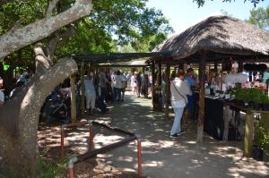 a group of people walking around a market with a thatch roof at TheBlueDoor in Greyton