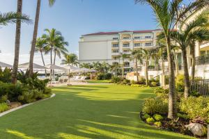a lawn in front of a hotel with palm trees at Eau Resort & Spa in South Palm Beach