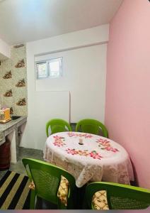 a room with a table with green chairs and a pink wall at Mountain View homestay in Darjeeling