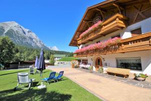 ein Gebäude mit Stühlen und einem Sonnenschirm im Hof in der Unterkunft Ivos Sonnenpension in Leutasch