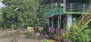 a green and white house with flowers in front of it at Coffee land in Kaniyāmbetta