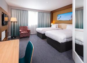 a hotel room with two beds and a chair at Holiday Inn Derby Riverlights by IHG in Derby +73 photos
