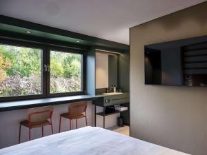 a bedroom with a bed and two chairs and a sink at vevio - Hotel & Events in Spiesen-Elversberg
