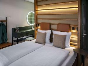 a bedroom with a large white bed with a headboard at vevio - Hotel & Events in Spiesen-Elversberg