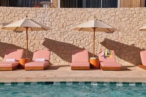 a group of chairs and umbrellas next to a pool at The Lodge Wadjemup in Rottnest Island