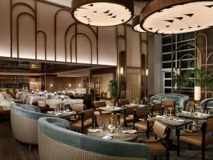 ein Restaurant mit Tischen, Stühlen und Kronleuchtern in der Unterkunft Sofitel Montreal Golden Mile in Montreal
