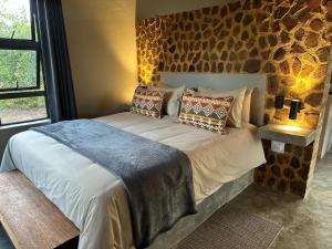 a bedroom with a large bed with a stone wall at Klipdrift Sands Game Lodge in Dinokeng Game Reserve