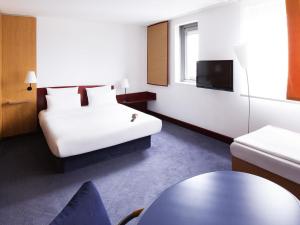 a hotel room with a bed and a tv at Novotel Suites Hannover in Hannover