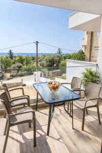a table with chairs and a bowl of fruit on a balcony at MPL Apartments & maisonettes in Limenaria