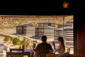 a man and woman sitting at a table in a restaurant at Petra Wassaif Camp in Wadi Musa