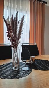 a table with a chair and a vase with flowers on it at Apartament OLIWIA 5 in Nowy Targ