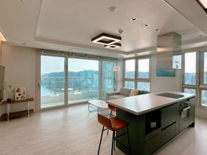 a kitchen with an island in a room with windows at Hyoi Stay Busan Songdo in Damyang