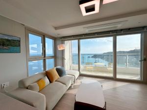 a living room with a couch and a large window at Hyoi Stay Busan Songdo in Damyang