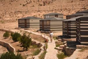 a person walking down a path in front of a building at Petra Wassaif Camp in Wadi Musa