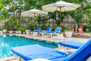 a swimming pool with blue chairs and umbrellas next to a pool at Summit Pavilion Hotel in Bangkok