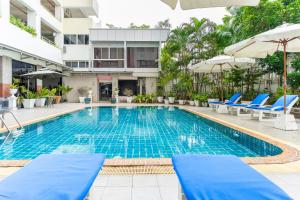 a swimming pool with blue chairs and umbrellas at a hotel at Summit Pavilion Hotel in Bangkok