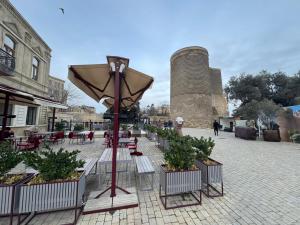 a patio with tables and chairs and an umbrella at Maiden Tower Prestige in Baku