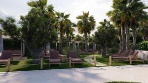 a row of chairs in a yard with palm trees at Cala Millor Garden Hotel - Adults Only in Cala Millor