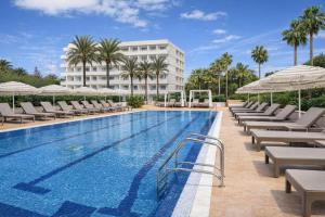 a swimming pool with lounge chairs and a building at Cala Millor Garden Hotel - Adults Only in Cala Millor