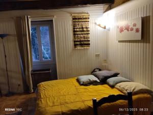 a bedroom with a bed with yellow sheets and a window at La Chambre Périgourdine in Journiac