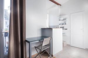 a desk with a chair in a room with a refrigerator at Hotel du Lys in Paris