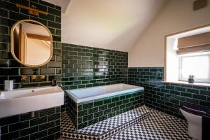 a bathroom with green tiles and a tub and a sink at The Old Vicarage Irton in Parton +30 photos