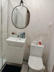 a white bathroom with a toilet and a mirror at Charmant appartement à Groslay in Groslay