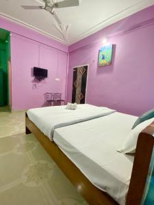 a bedroom with a large bed with purple walls at Juihal Residency & Kitchen in Kāziranga
