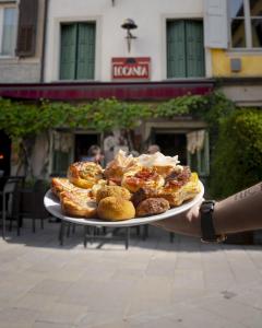 a person holding a plate of pastries and donuts at Locanda Al Cappello in Udine