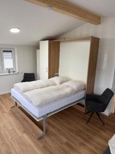 a bedroom with a large bed and a chair at Ferienwohnung Theus in Albersdorf