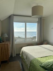 a bedroom with a bed and a large window with the ocean at Villa Denise Petit Gîte in Barneville-Carteret +11 photos