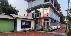 a pink and blue building with a sign on it at Juihal Residency & Kitchen in Kāziranga +16 photos