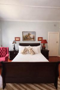 a bedroom with a large bed and a red chair at La Cura Stay in Johannesburg