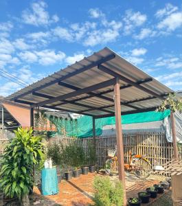 a wooden pergola in a garden with a fence at Stay Like a Local เต็นท์บ้านเรา in Chiang Mai