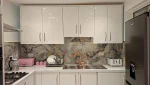 a kitchen with white cabinets and a sink at The White House in Moston