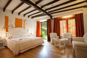 a bedroom with a white bed and chairs and windows at Hotel Doña Teresa in La Alberca