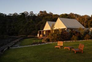 a house with two chairs in the grass next to a building at Risby Cove Boutique Hotel in Strahan +98 photos