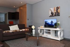 a living room with a couch and a tv on a table at The Orange Corner III in Johannesburg