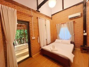 a bedroom with a bed and a large window at An Tiên Ecolodge in Tân Phú