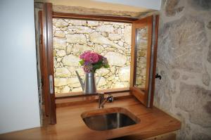 La salle de bains est pourvue d'un lavabo et d'une fenêtre ornée d'un vase de fleurs. dans l'établissement Casinhas da Levada, à Sobredo