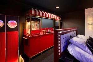 a room with a bed and a kitchen with red cabinets at Appartement Cinéma Ecran géant & Dolby Atmos in Niort